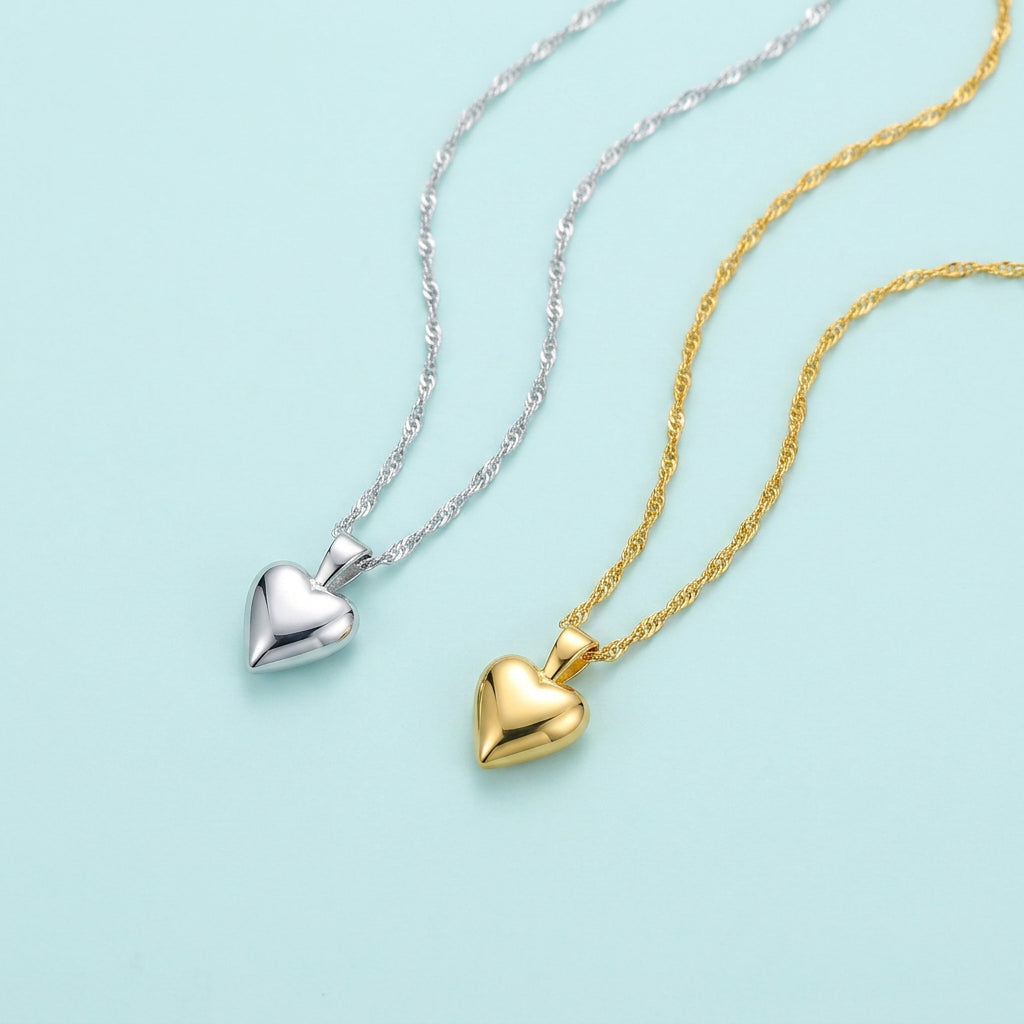 Silver and gold heart pendant water-wave chain necklaces on pale blue background