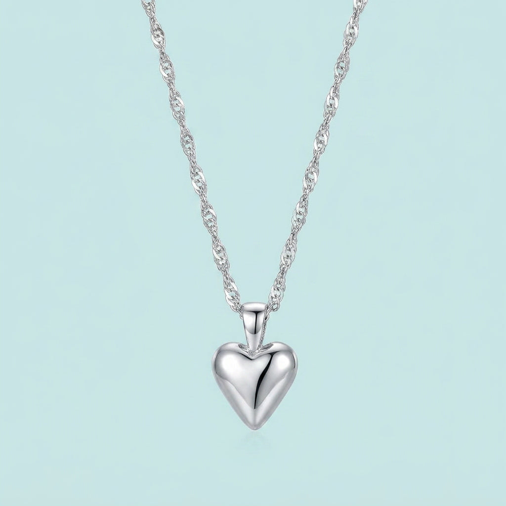 Silver heart pendant on water-wave chain, pale blue background