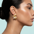 Model wearing satin gold flower CZ stud earrings